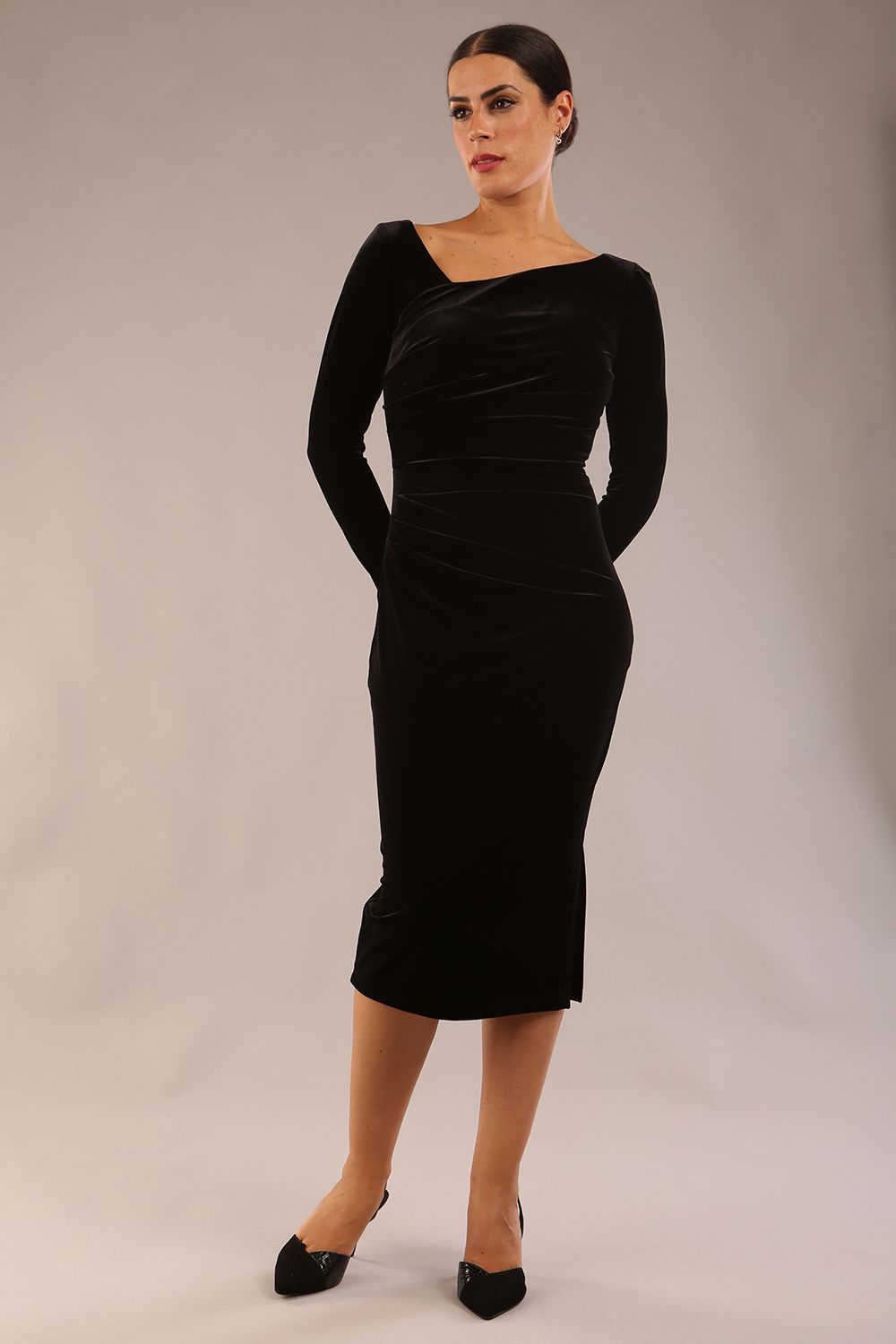 model is wearing a diva catwalk Renoir Long Sleeve Velvet Dress long sleeves midi length with side vent and asymmetric neckline and pleating details in black velvet