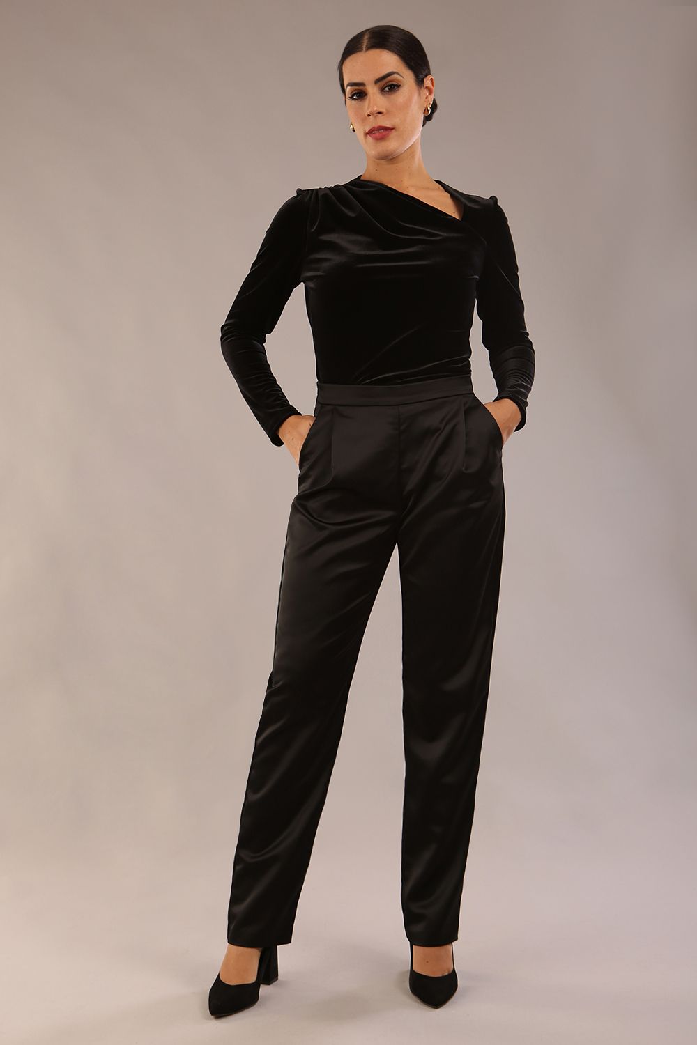 model is wearing a diva catwalk Rhea Satin Stretch Trousers with side pockets and concealed side zip and long leg in black satin