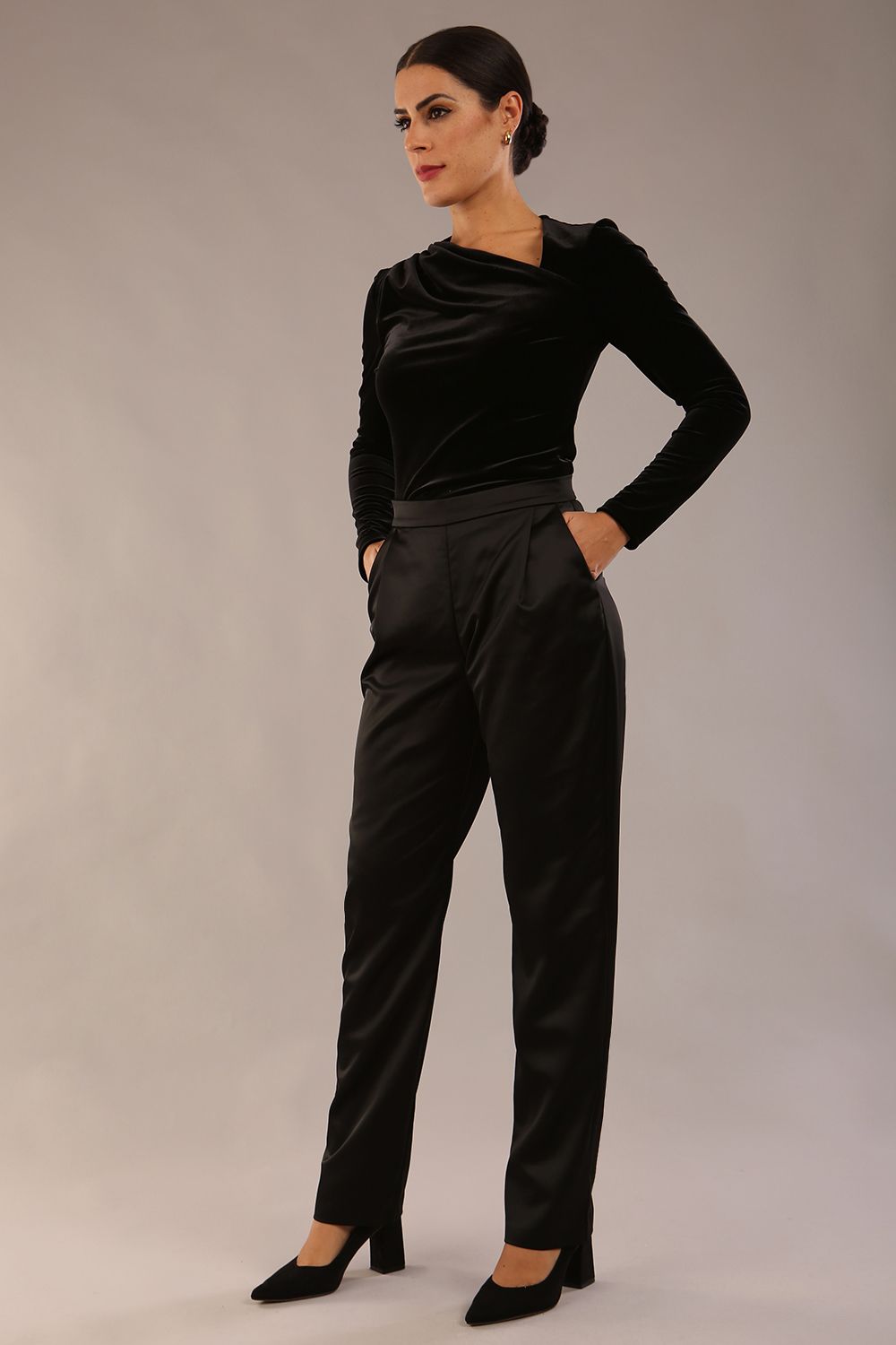 model is wearing a diva catwalk Rhea Satin Stretch Trousers with side pockets and concealed side zip and long leg in black satin