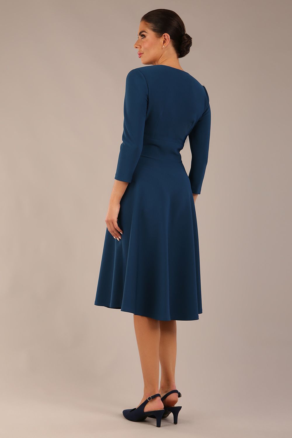 brunette model is wearing a diva catwalk Haddington sleeved A-line Dress knee length round neckline with crossover v-slit detail in teal colour back image