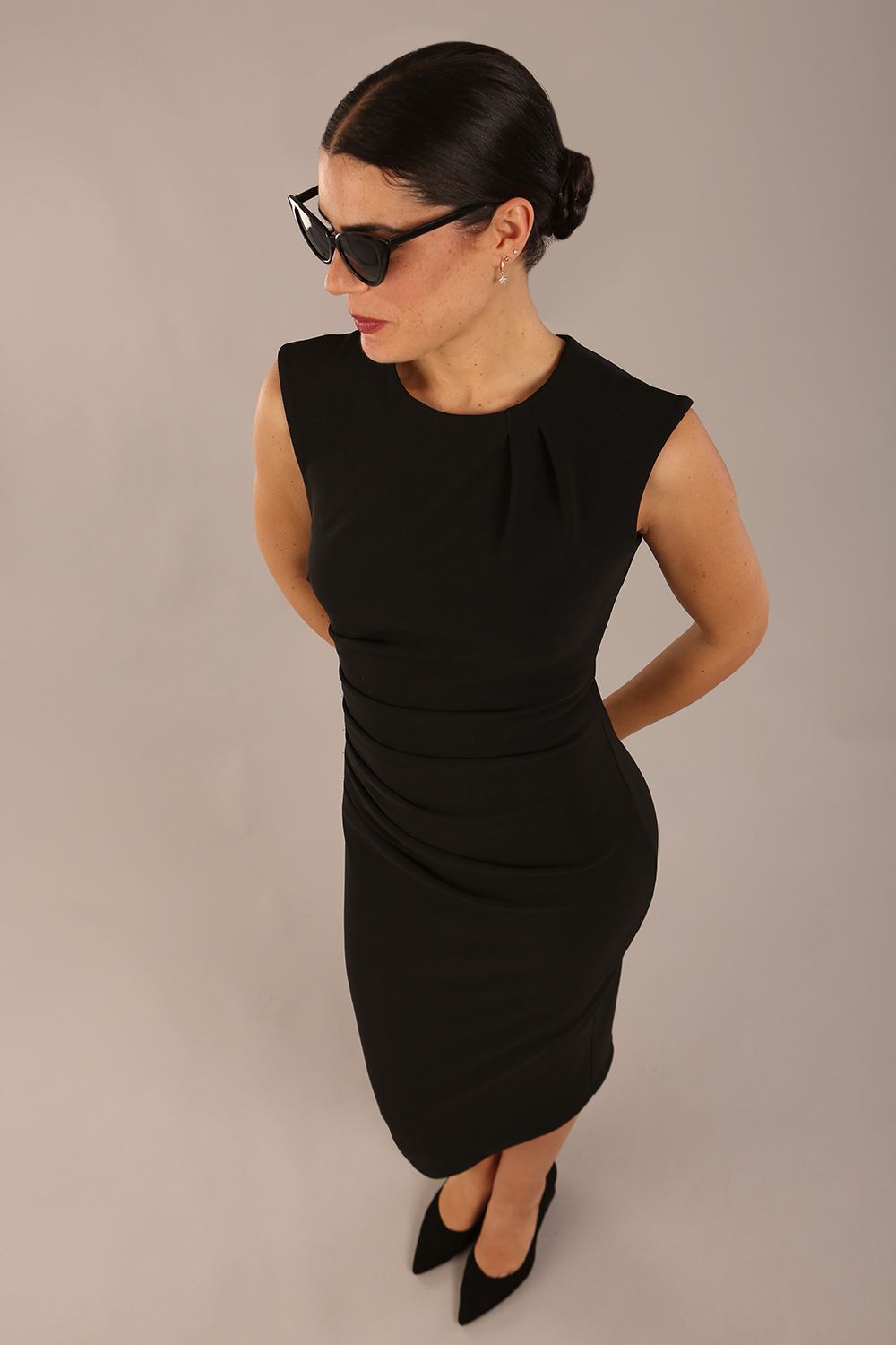 model is wearing a diva catwalk sleeveless dress with round neckline with pleating details and knee length in black colour front top