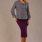 Model wearing a long-sleeved Clifton top in Jardin Secret print with a tie neckline and frill cuffs, styled with a purple pencil skirt.