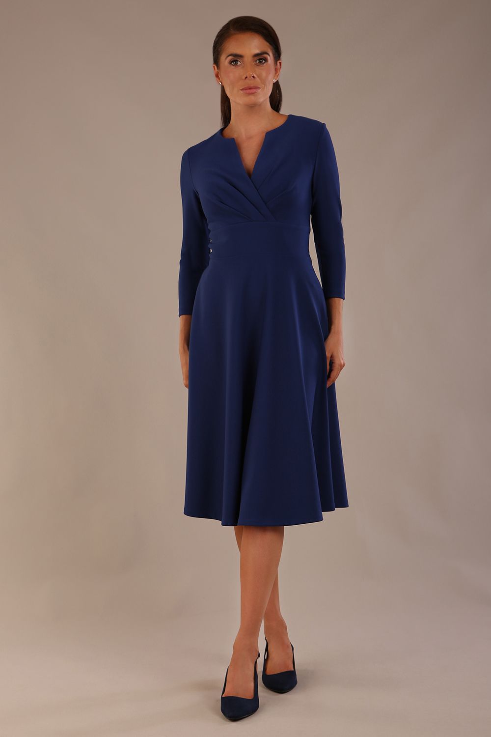 brunette model is wearing a diva catwalk Haddington sleeved A-line Dress knee length round neckline with crossover v-slit detail in navy blue colour front image