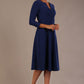 brunette model is wearing a diva catwalk Haddington sleeved A-line Dress knee length round neckline with crossover v-slit detail in navy blue colour front side image