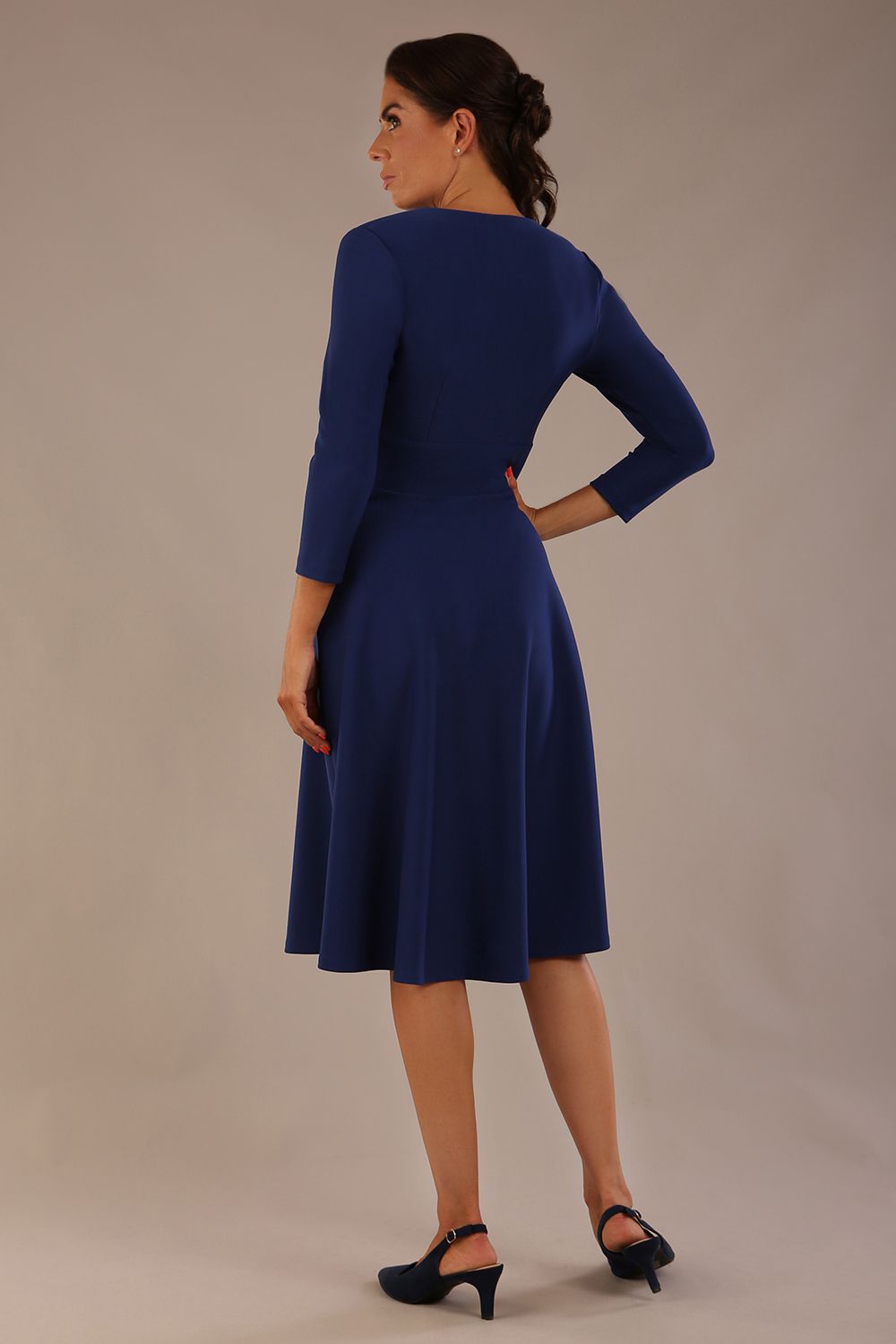 brunette model is wearing a diva catwalk Haddington sleeved A-line Dress knee length round neckline with crossover v-slit detail in navy blue colour back image