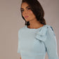 brunette model is wearing a diva catwalk Reverie Short Sleeve Stretch Pencil Dress with Bow Detail in sky blue colour front image close up