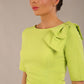 brunette model is wearing a diva catwalk Reverie Short Sleeve Stretch Pencil Dress with Bow Detail in lime green colour front image close up