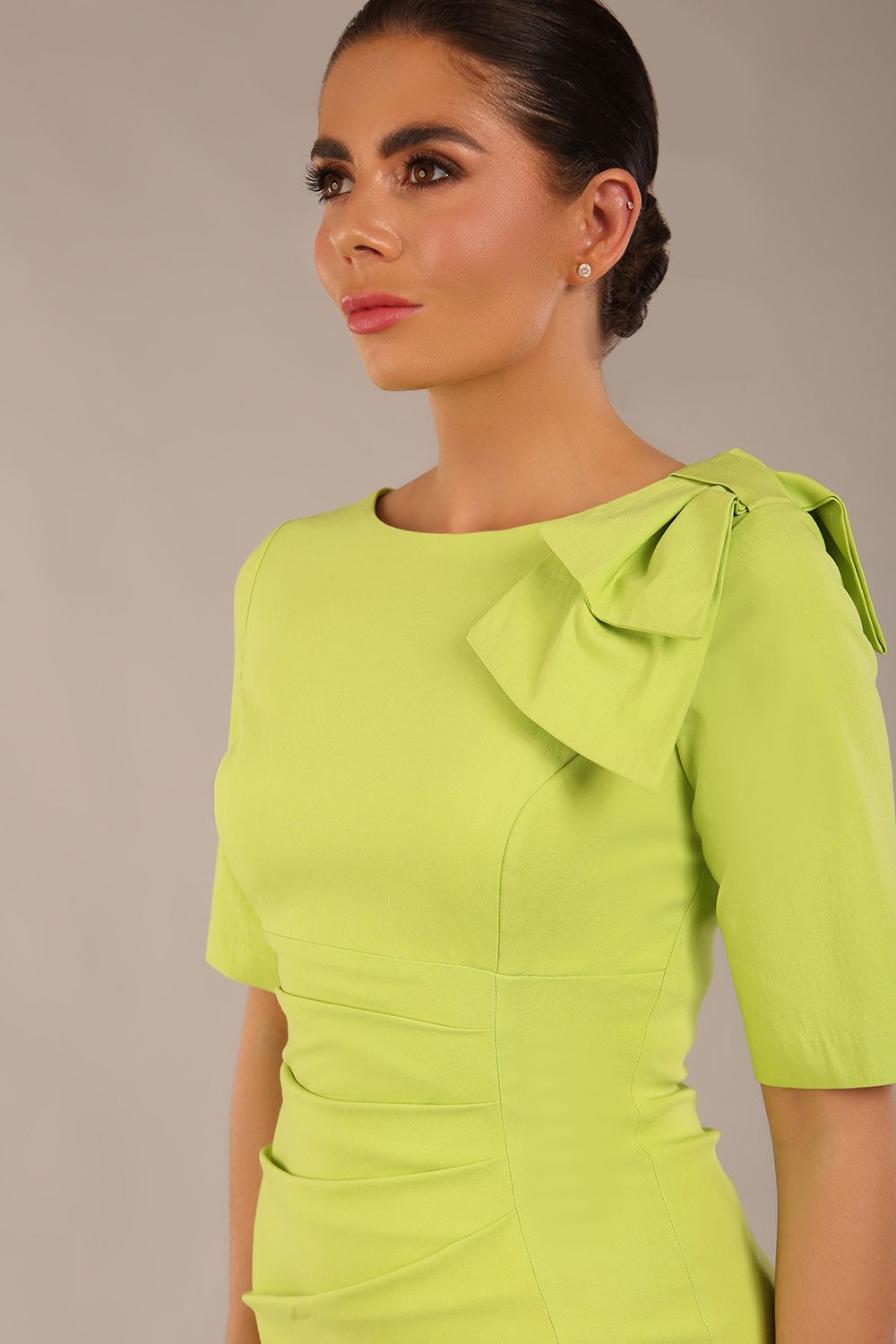 brunette model is wearing a diva catwalk Reverie Short Sleeve Stretch Pencil Dress with Bow Detail in lime green colour front image close up