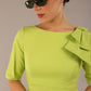 brunette model is wearing a diva catwalk Reverie Short Sleeve Stretch Pencil Dress with Bow Detail in lime green colour front image close up with sunglasses