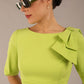 brunette model is wearing a diva catwalk Reverie Short Sleeve Stretch Pencil Dress with Bow Detail in lime green colour front image close up with sunglasses
