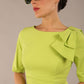 brunette model is wearing a diva catwalk Reverie Short Sleeve Stretch Pencil Dress with Bow Detail in lime green colour front image with sunglasses