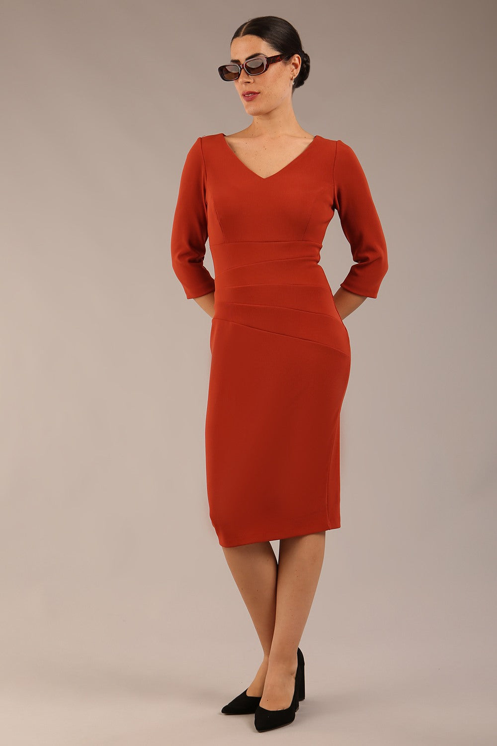 brunette model is wearing a  diva catwalk Tara V-neckline Sleeved Pencil Dress knee length in terracotta brown colour front image with sunglasses