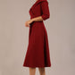 brunette model is wearing a diva catwalk Fabienne sleeved A-line Dress with pockets v neckline knee length wide waistband fold over v neckline in burgundy colour front image