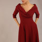 brunette model is wearing a diva catwalk Fabienne sleeved A-line Dress with pockets v neckline knee length wide waistband fold over v neckline in burgundy colour front image