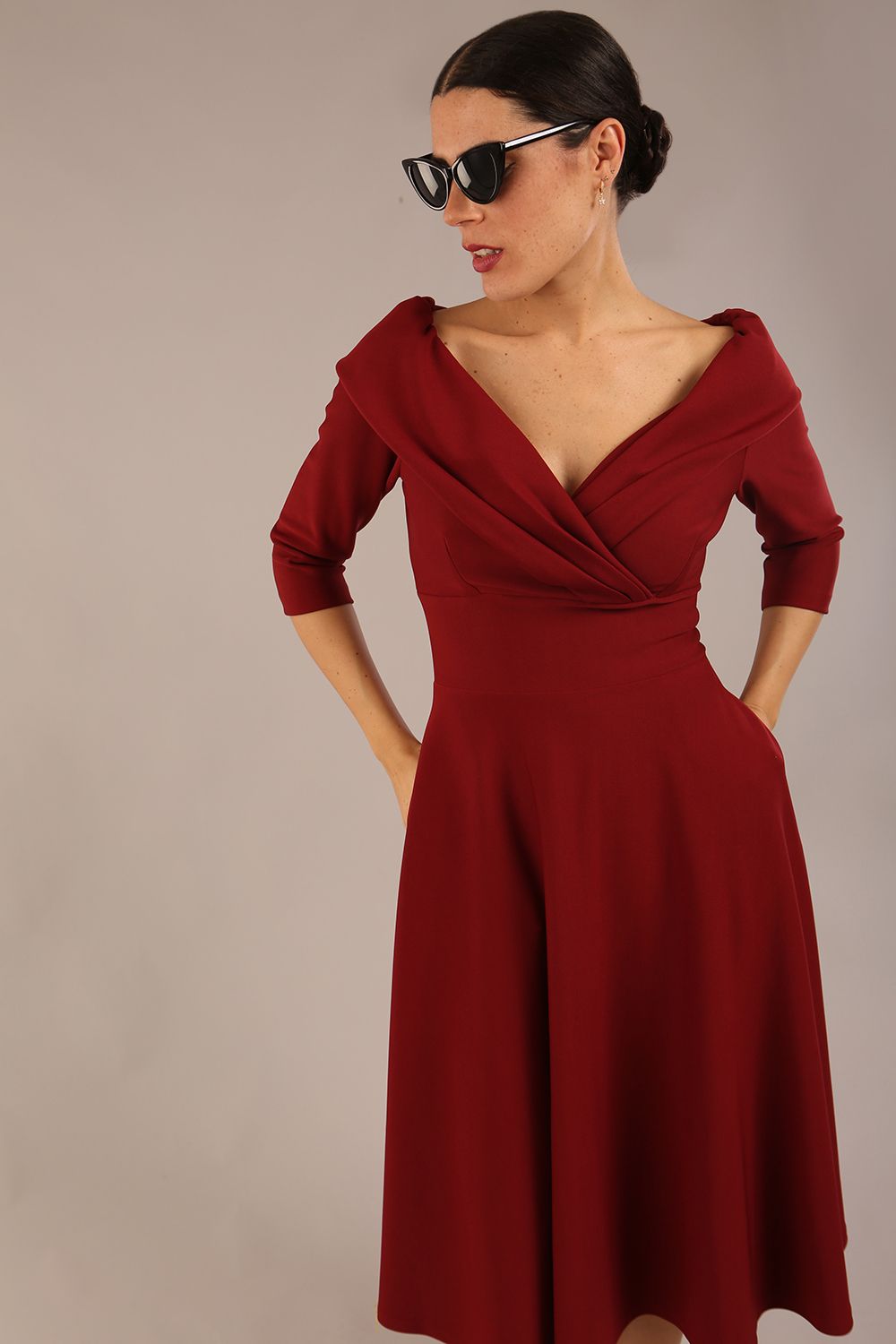 brunette model is wearing a diva catwalk Fabienne sleeved A-line Dress with pockets v neckline knee length wide waistband fold over v neckline in burgundy colour front image