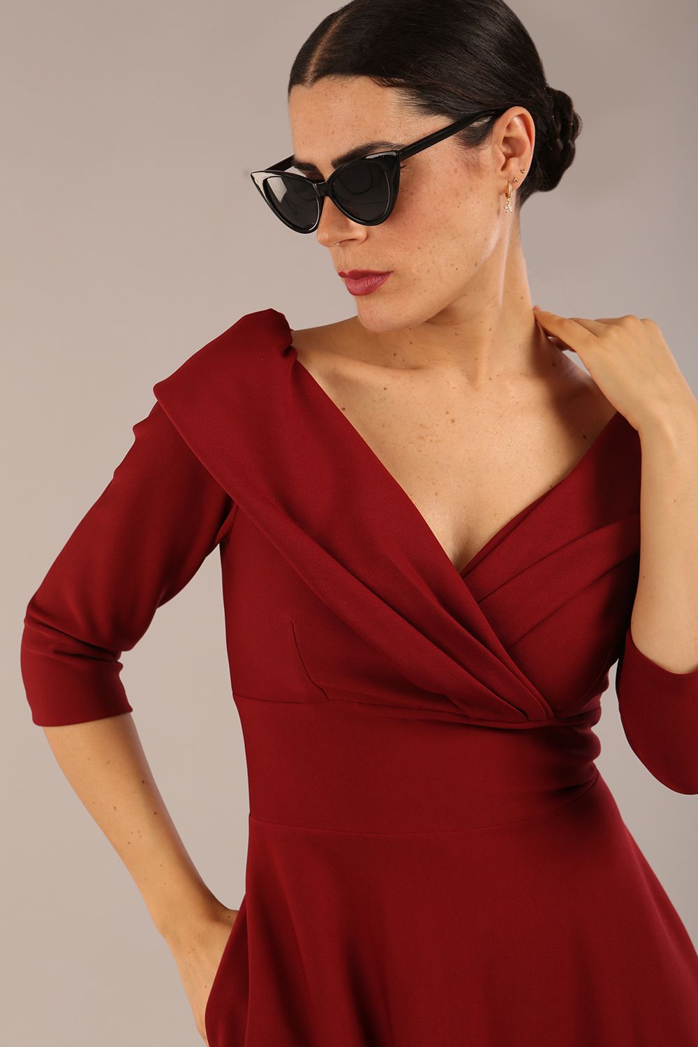 brunette model is wearing a diva catwalk Fabienne sleeved A-line Dress with pockets v neckline knee length wide waistband fold over v neckline in burgundy colour front image close up