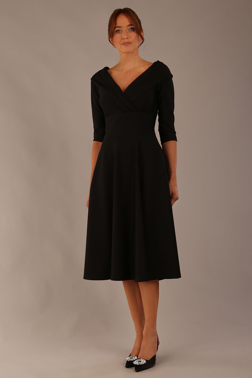 brunette model is wearing a diva catwalk Fabienne sleeved A-line Dress with pockets v neckline knee length wide waistband fold over v neckline in black colour front image