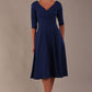 brunette model is wearing a diva catwalk Fabienne sleeved A-line Dress with pockets v neckline knee length wide waistband fold over v neckline in navy blue colour front image