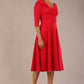 brunette model is wearing a diva catwalk Fabienne sleeved A-line Dress with pockets v neckline knee length wide waistband fold over v neckline in electric red colour front side image
