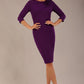 brunette model is wearing a diva catwalk Mirabelle ¾ Sleeves & Floral Shoulder Detail Pencil Dress with diagonal pleating across the front knee length in purple colour front image