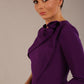 brunette model is wearing a diva catwalk Mirabelle ¾ Sleeves & Floral Shoulder Detail Pencil Dress with diagonal pleating across the front knee length in purple colour front image close up
