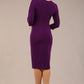 brunette model is wearing a diva catwalk Mirabelle ¾ Sleeves & Floral Shoulder Detail Pencil Dress with diagonal pleating across the front knee length in purple colour back image