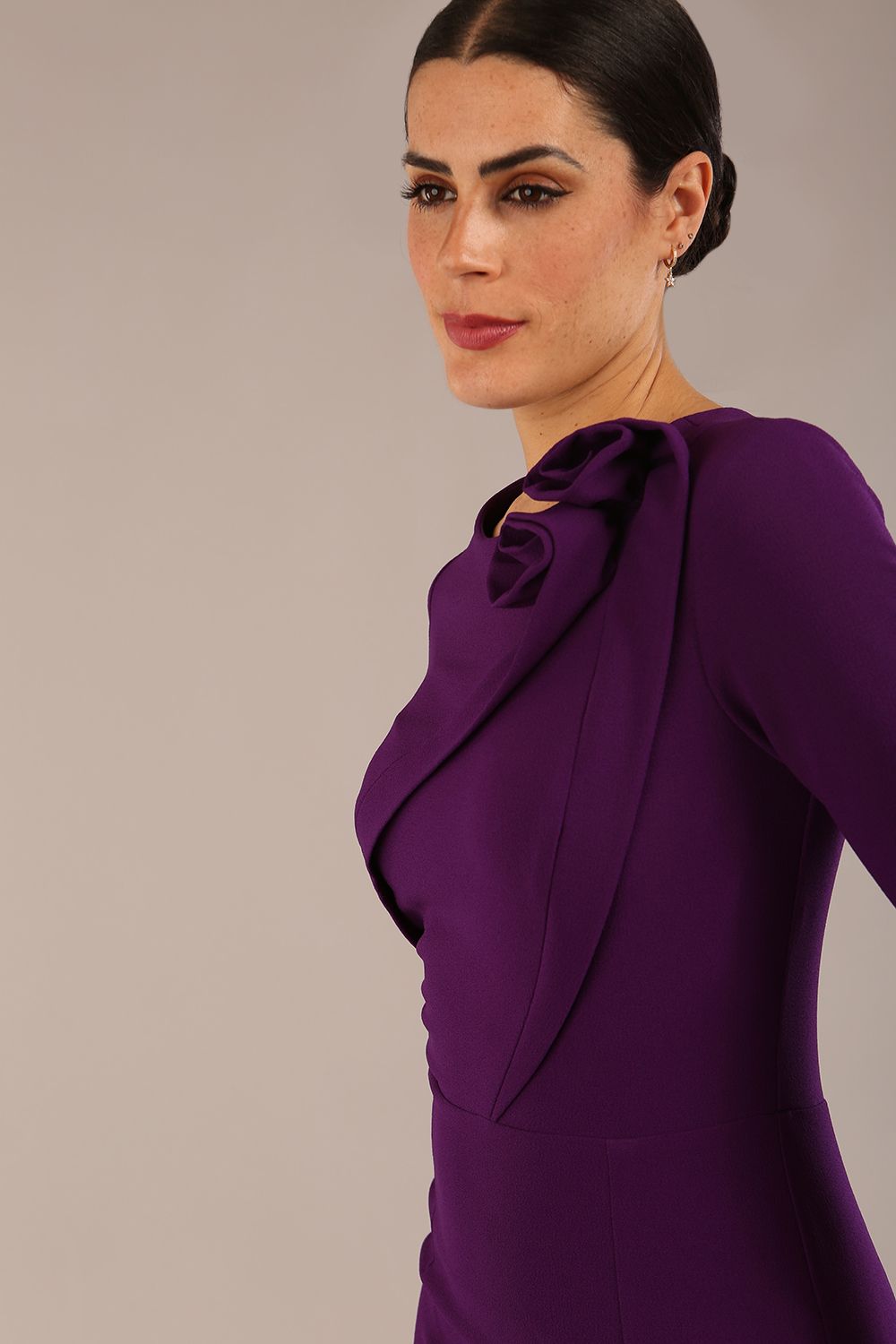 brunette model is wearing a diva catwalk Mirabelle ¾ Sleeves & Floral Shoulder Detail Pencil Dress with diagonal pleating across the front knee length in purple colour front image close up