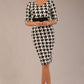 brunette model is wearing a diva catwalk OP-ART V-Neck Sleeved Monochrome Pencil Dress with black waistband and flower detail in a Super stretch dogtooth fabric black and white print front image