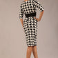 brunette model is wearing a diva catwalk OP-ART V-Neck Sleeved Monochrome Pencil Dress with black waistband and flower detail in a Super stretch dogtooth fabric black and white print back image