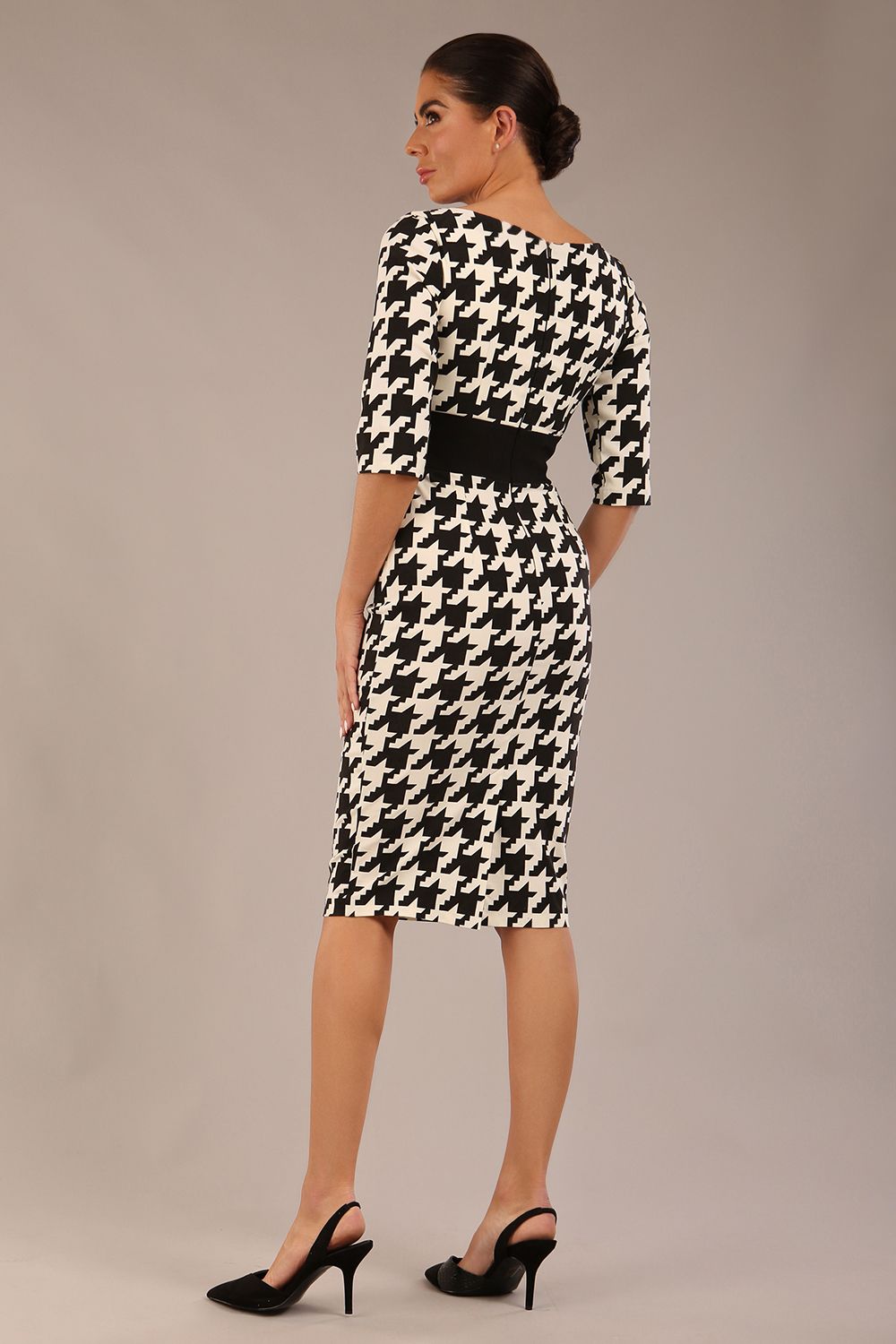 brunette model is wearing a diva catwalk OP-ART V-Neck Sleeved Monochrome Pencil Dress with black waistband and flower detail in a Super stretch dogtooth fabric black and white print front image