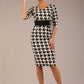 brunette model is wearing a diva catwalk OP-ART V-Neck Sleeved Monochrome Pencil Dress with black waistband and flower detail in a Super stretch dogtooth fabric black and white print front image