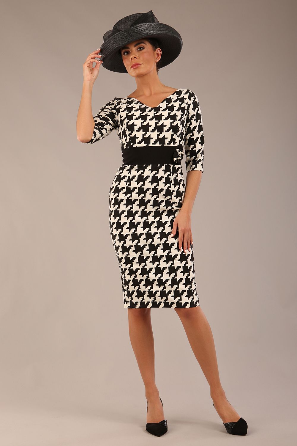 brunette model is wearing a diva catwalk OP-ART V-Neck Sleeved Monochrome Pencil Dress with black waistband and flower detail in a Super stretch dogtooth fabric black and white print front image