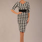 brunette model is wearing a diva catwalk OP-ART V-Neck Sleeved Monochrome Pencil Dress with black waistband and flower detail in a Super stretch dogtooth fabric black and white print front image