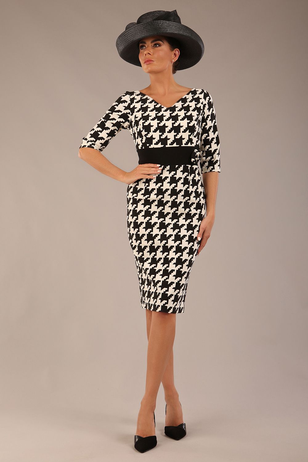brunette model is wearing a diva catwalk OP-ART V-Neck Sleeved Monochrome Pencil Dress with black waistband and flower detail in a Super stretch dogtooth fabric black and white print front image