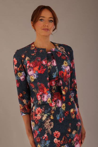 Model wearing the Valetta cropped floral jacquard jacket over a matching dress with a plain background (Hidcote Floral)