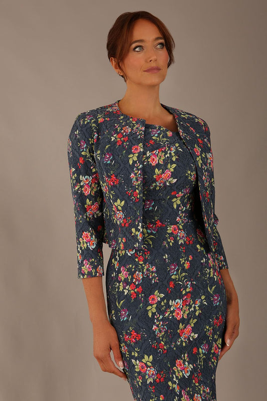 Model wearing the Valetta cropped floral jacquard jacket over a matching dress with a plain background (Navy Floral)