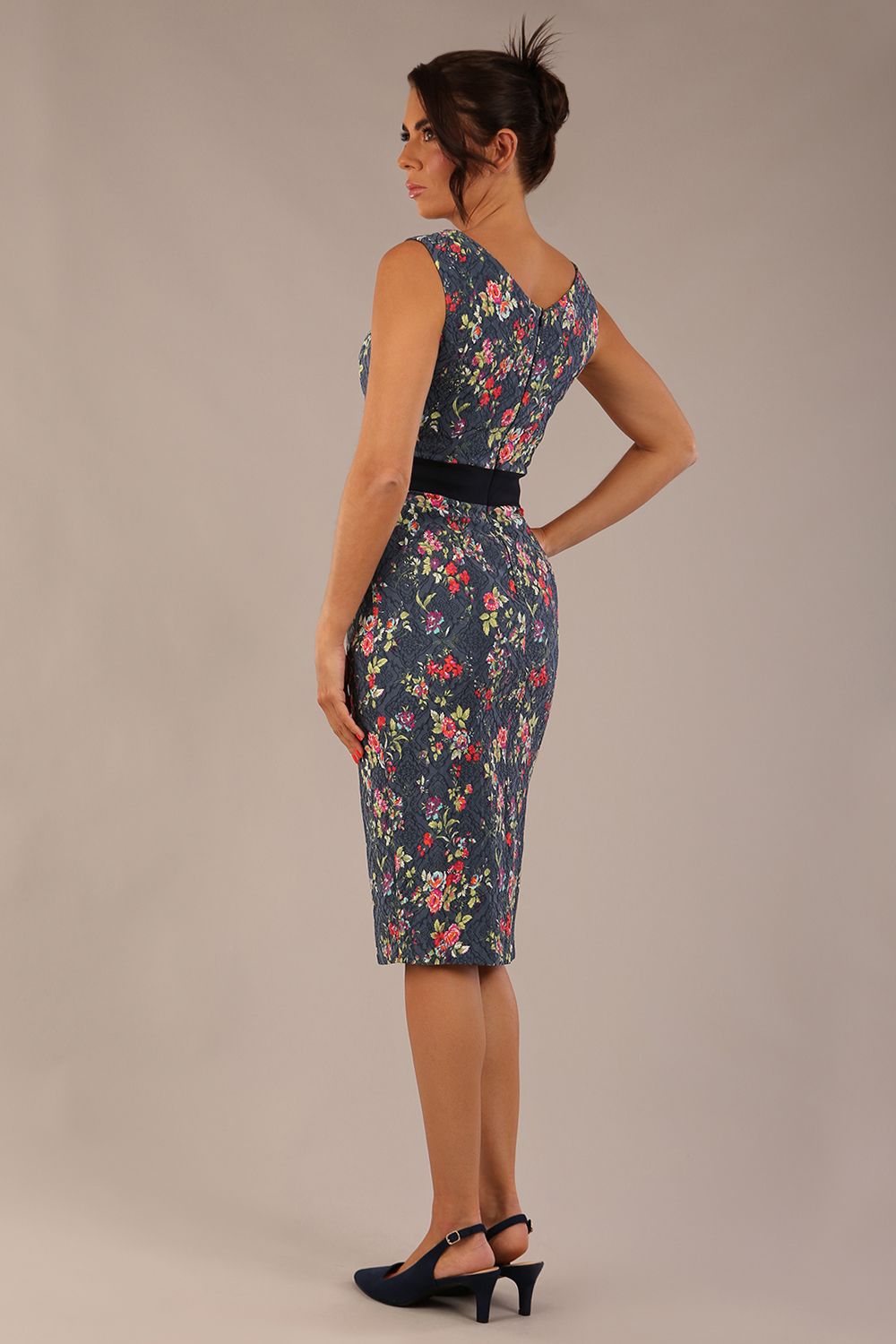 brunette model is wearing a diva catwalk June Floral Sleeveless Navy Waistband Pencil Dress in floral blue print back image