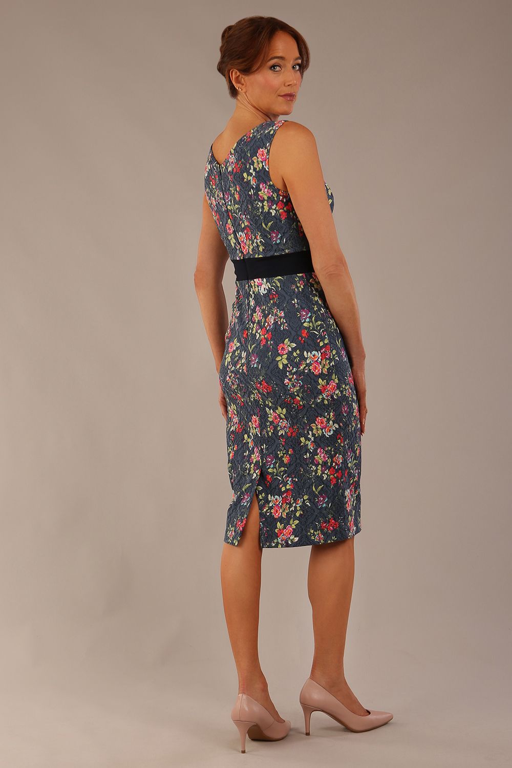 brunette model is wearing a diva catwalk June Floral Sleeveless Navy Waistband Pencil Dress in floral blue print back image