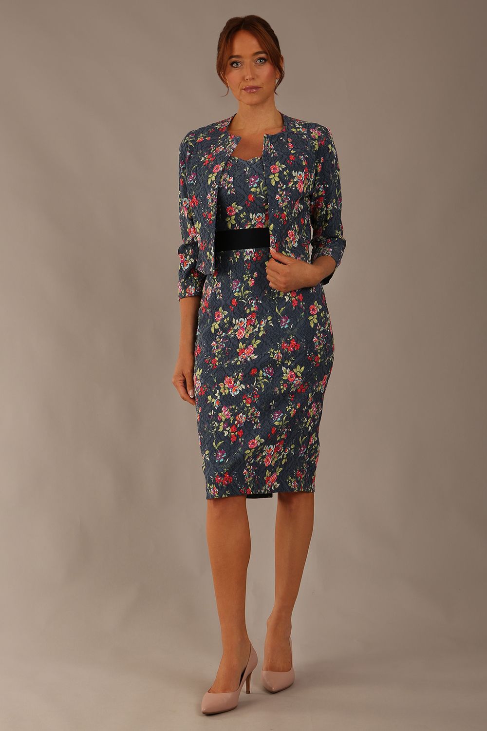 brunette model is wearing a diva catwalk June Floral Sleeveless Navy Waistband Pencil Dress in floral blue print front image with valetta jacket