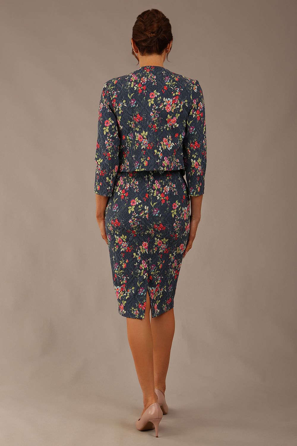 brunette model is wearing a diva catwalk June Floral Sleeveless Navy Waistband Pencil Dress in floral blue print back image with valetta jacket