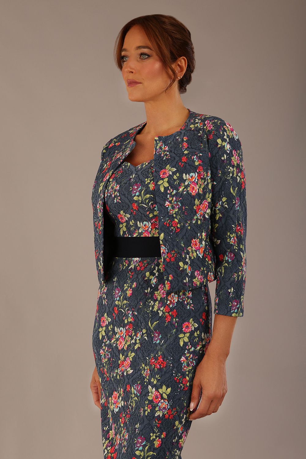 brunette model is wearing a diva catwalk June Floral Sleeveless Navy Waistband Pencil Dress in floral blue print front image with valetta jacket