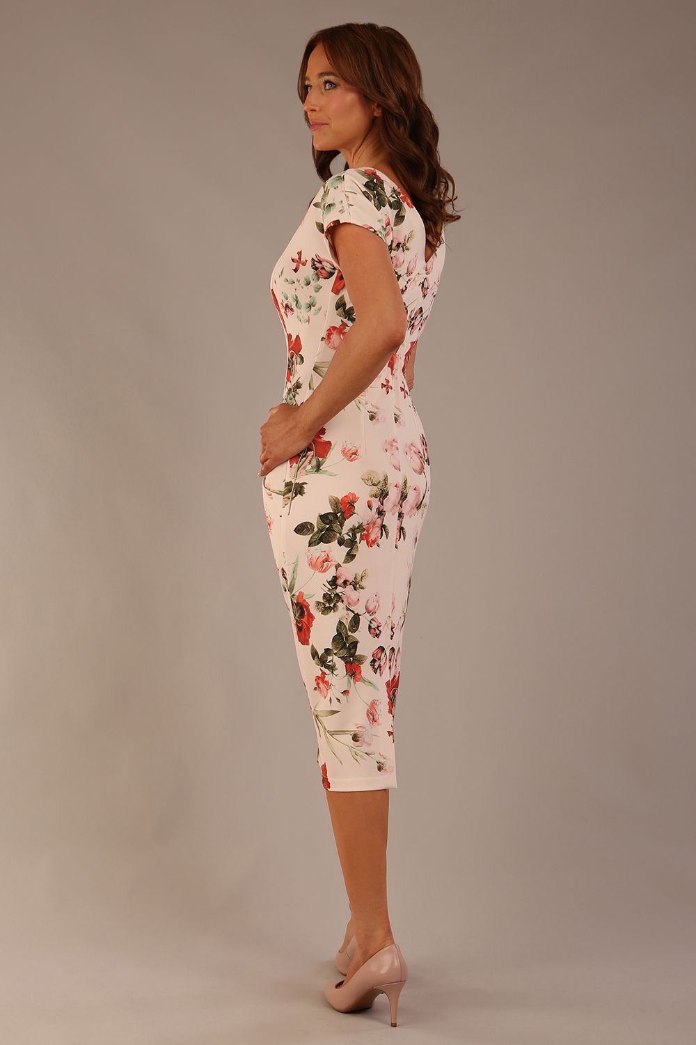 brunette model is wearing a 7002 diva catwalk Carlisle Boat Neck Short Sleeve Midi Pencil Dress in Rose Blush print with side pockets back side