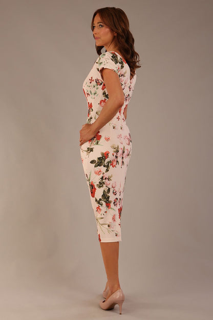 brunette model is wearing a 7002 diva catwalk Carlisle Boat Neck Short Sleeve Midi Pencil Dress in Rose Blush print with side pockets back side