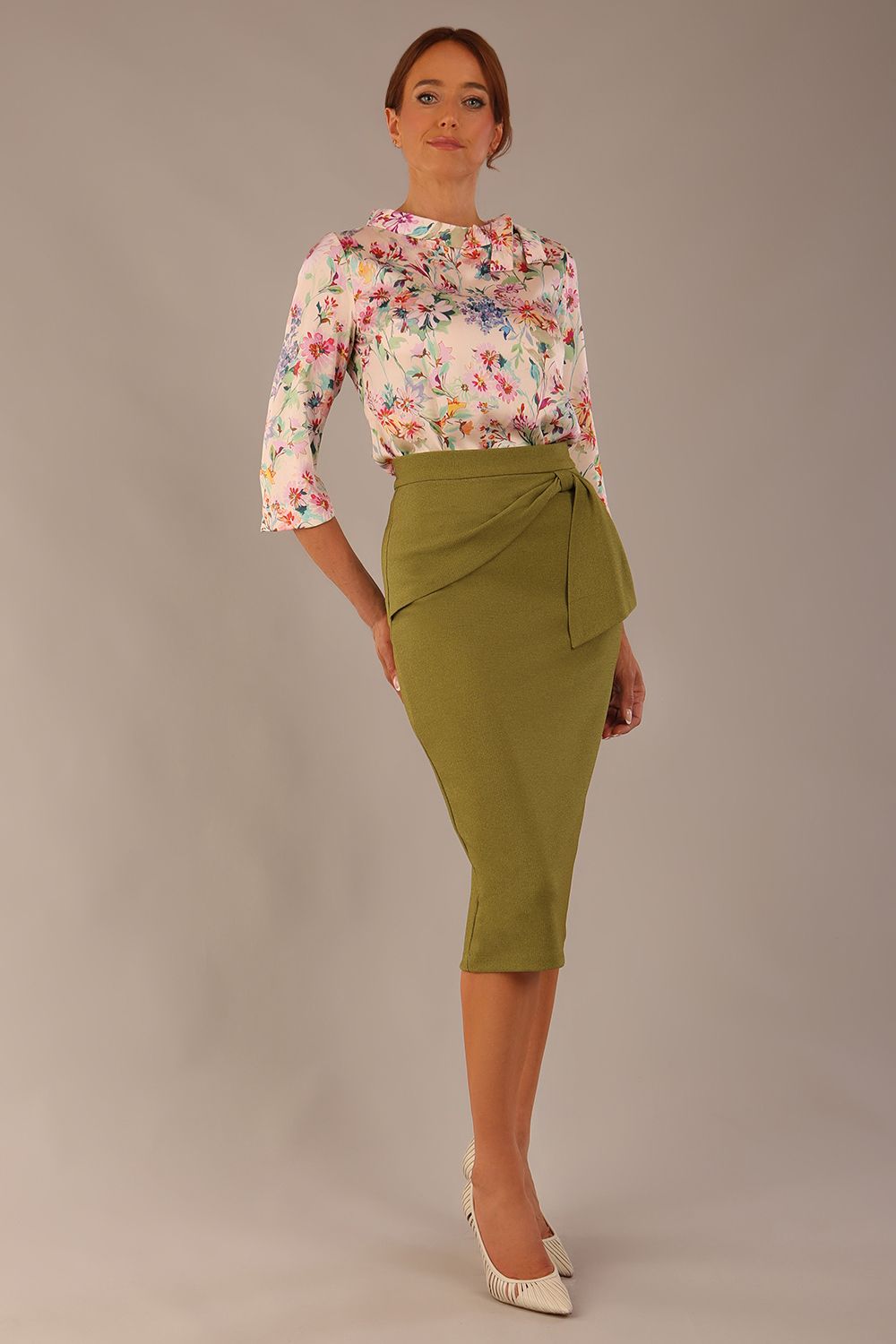 Model wearing the Rockwell 3/4 sleeve satin top in Lush Garden print, styled with an olive green pencil skirt.
