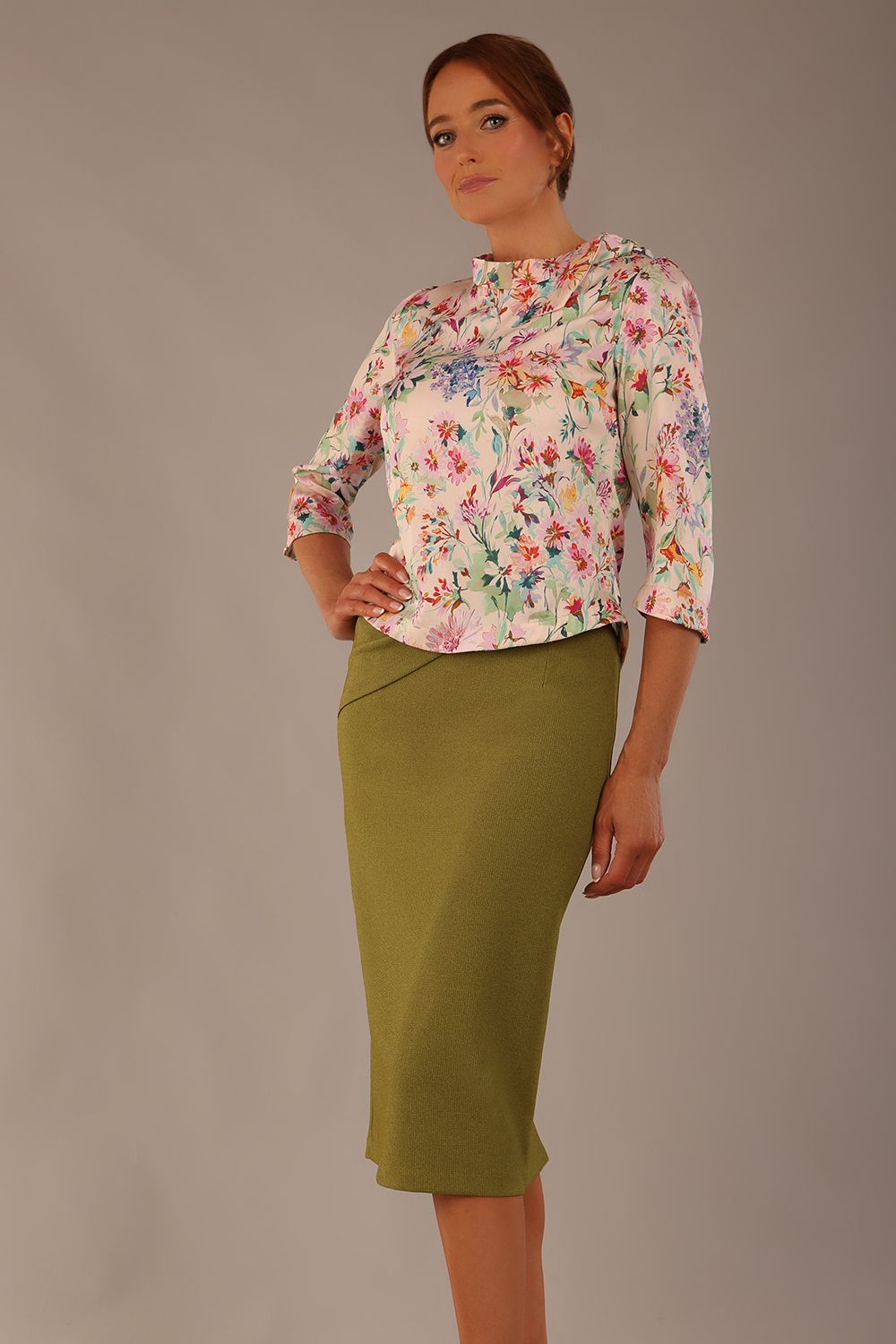 Model wearing the Rockwell 3/4 sleeve satin top in Lush Garden print, styled with an olive green pencil skirt.