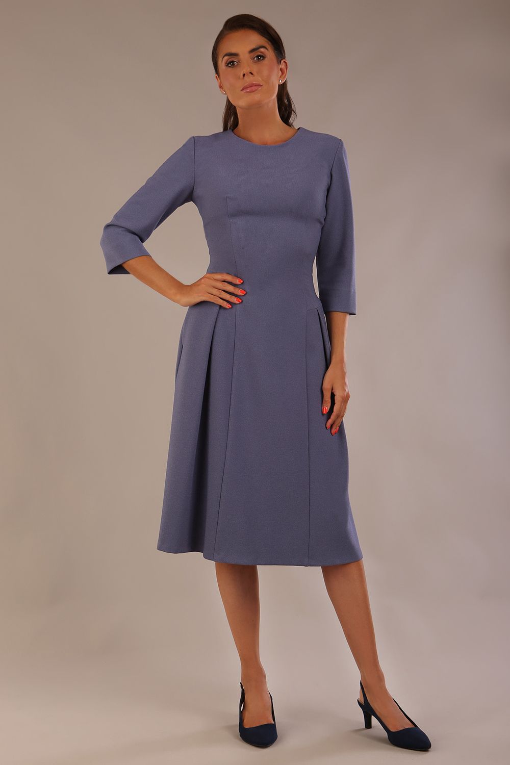 Model wearing the Ario pleated A-line dress in blue mineral, showcasing the round neckline and 3/4 sleeves.