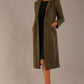 Woman wearing a long olive green Ambrose Boucle Midi Coat over a black Rialto sleeveless pencil dress on a plain background