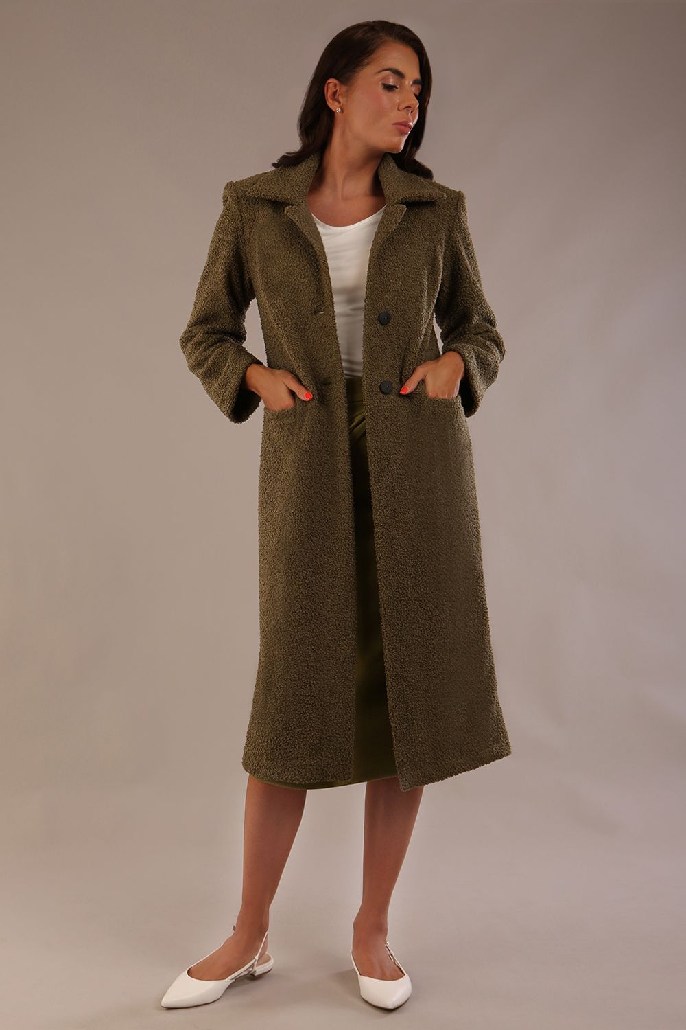 Model wearing the Ambrose boucle midi coat in olive green with hands in the side pockets.