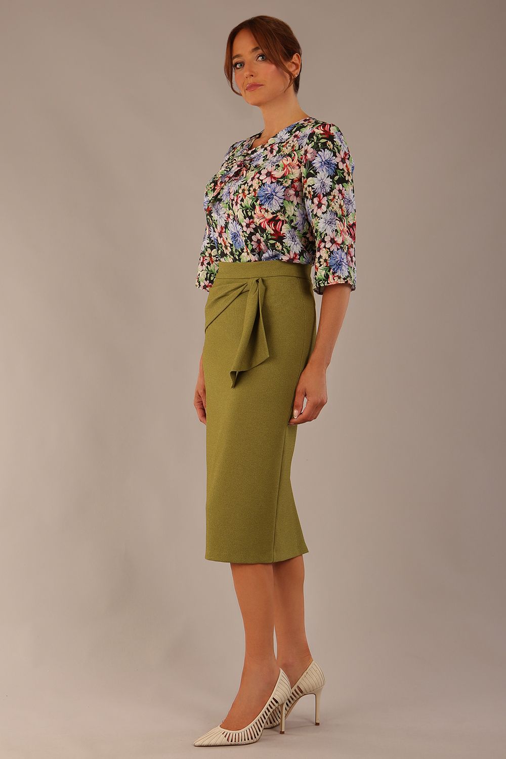 Model wearing a Suki asymmetric draped top in the Aurora Botanical print, styled with a olive green pencil skirt.