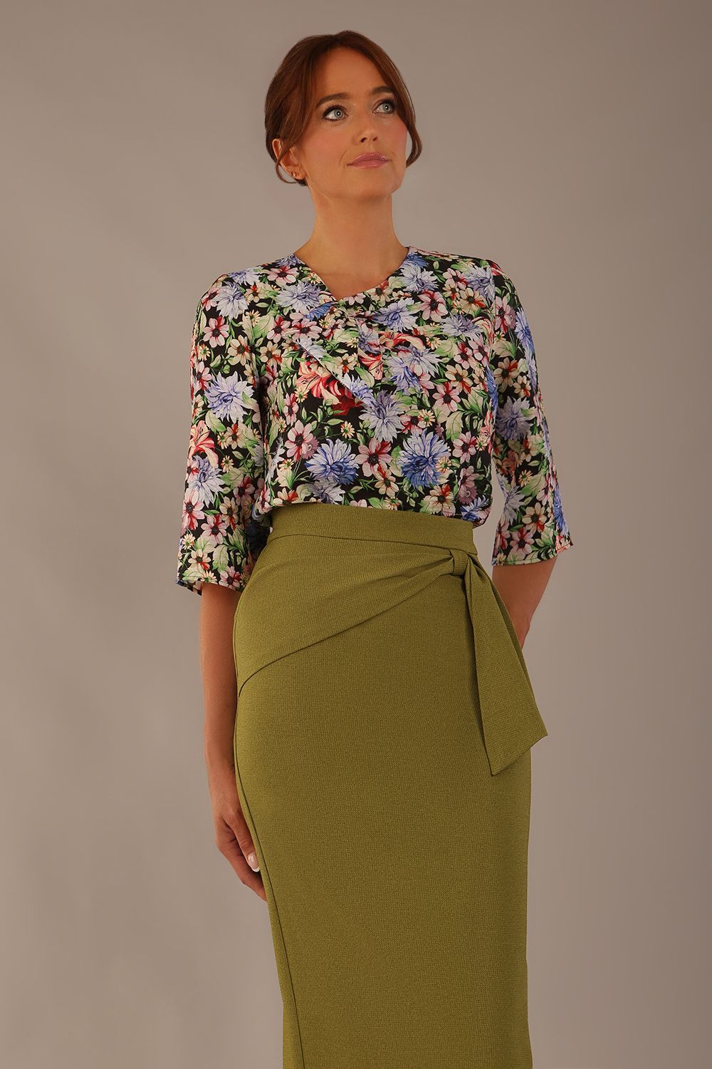 Model wearing a Suki asymmetric draped top in the Aurora Botanical print, styled with a olive green pencil skirt.